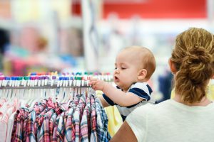 Mature caucasian woman holding her baby while shopping in a megastore
